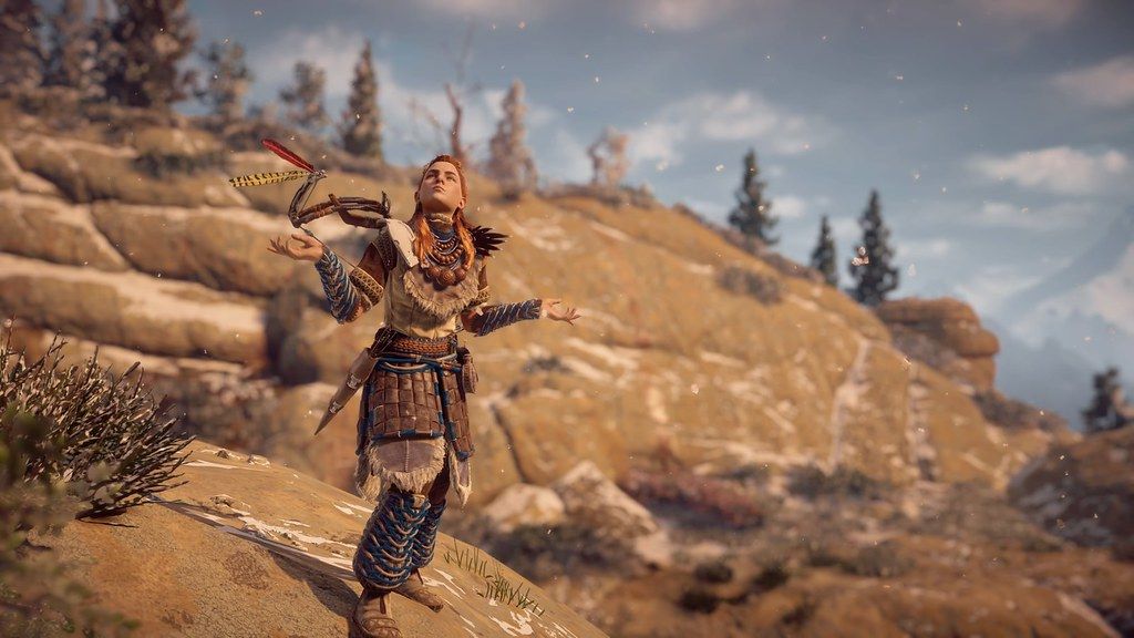 Fragment gry Horizon: Zero Dawn. Główna bohaterka, śnieg, wzgórza, góry.