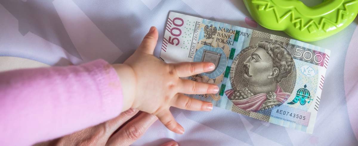 fot: Arkadiusz Ziolek/ East News. 23.05.2019. n/z Dlon dziecka i matki na tle zabawek i banknotu 500 zl.